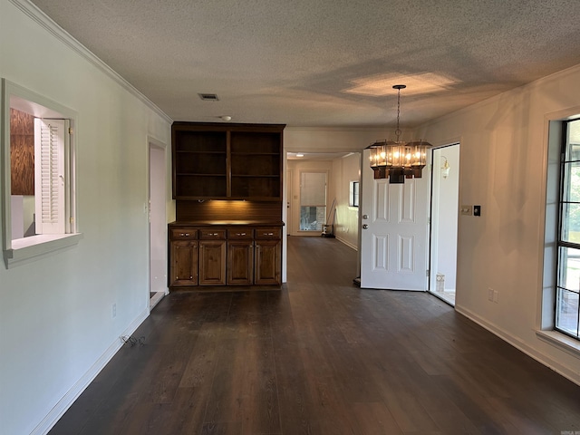 interior space featuring ornamental molding, dark hardwood / wood-style flooring, a chandelier, and a textured ceiling