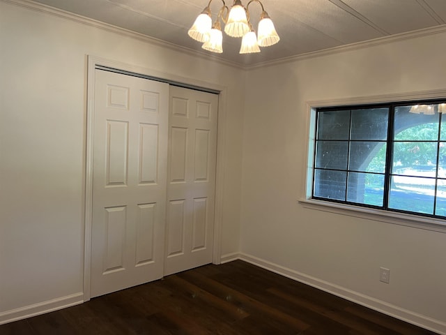 unfurnished bedroom with crown molding, dark hardwood / wood-style floors, ceiling fan with notable chandelier, and a closet