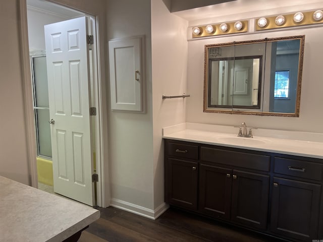 bathroom featuring hardwood / wood-style flooring, vanity, and bath / shower combo with glass door