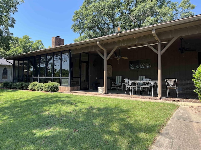 rear view of house featuring ceiling fan, a yard, a patio, and a sunroom