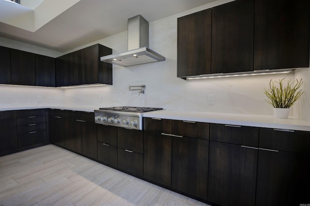 kitchen featuring light wood-type flooring, tasteful backsplash, dark brown cabinetry, ventilation hood, and stainless steel gas stovetop