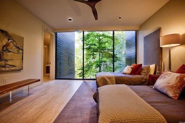 bedroom featuring ceiling fan, light wood-type flooring, and a wall of windows