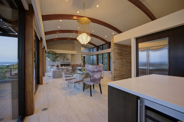 kitchen with lofted ceiling, built in refrigerator, decorative light fixtures, brick ceiling, and beverage cooler