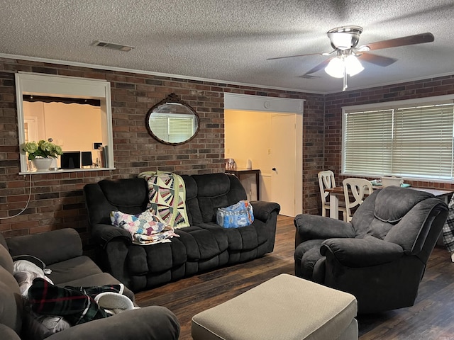 living room featuring dark wood-style floors, brick wall, and a textured ceiling