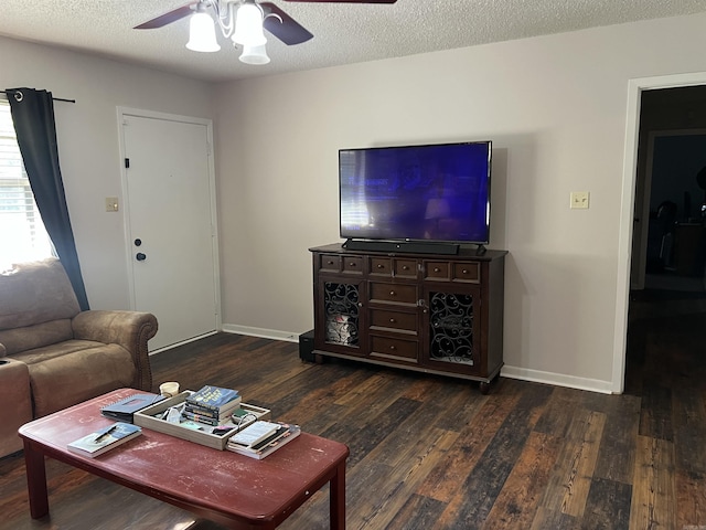 living area with dark wood-style floors, ceiling fan, a textured ceiling, and baseboards