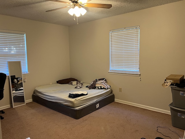 bedroom with ceiling fan, baseboards, dark colored carpet, and a textured ceiling