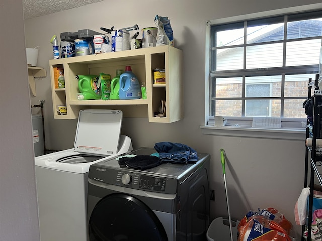 clothes washing area with a textured ceiling, laundry area, water heater, and washer and dryer