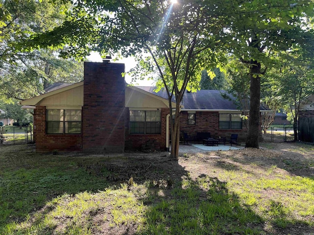 back of property featuring brick siding, fence, and a chimney