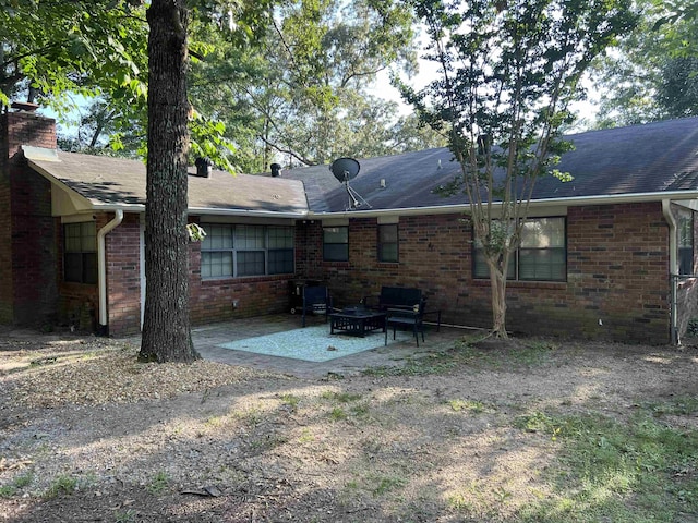 back of house featuring brick siding, a chimney, and a patio area