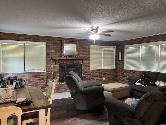 living area with a fireplace, dark wood finished floors, a textured ceiling, and brick wall