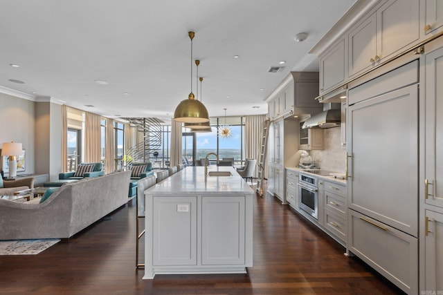 kitchen with dark hardwood / wood-style flooring, oven, a kitchen island with sink, and sink