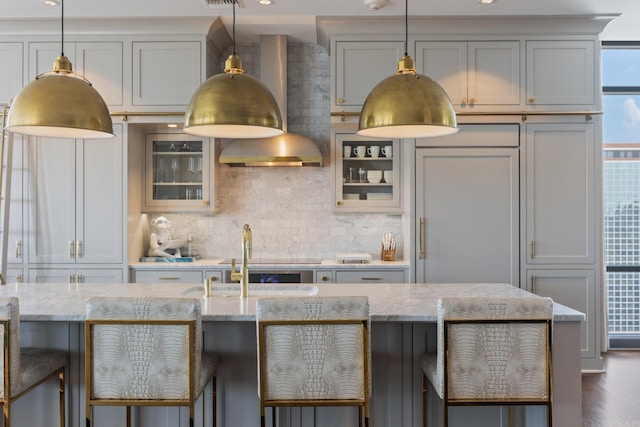 kitchen featuring wood-type flooring, light stone countertops, and wall chimney range hood