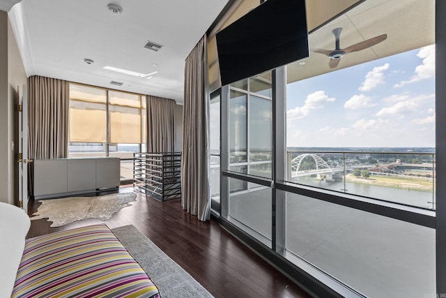 bedroom with hardwood / wood-style flooring, a water view, multiple windows, and a wall of windows