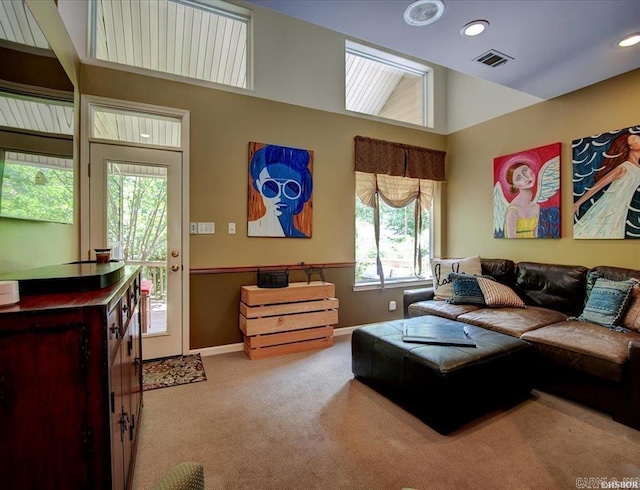 living room with a towering ceiling, carpet, and plenty of natural light