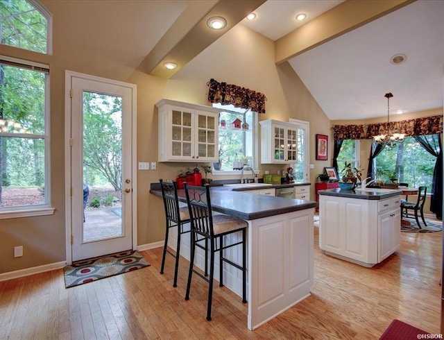 kitchen featuring a chandelier, hanging light fixtures, white cabinets, a kitchen island, and beam ceiling