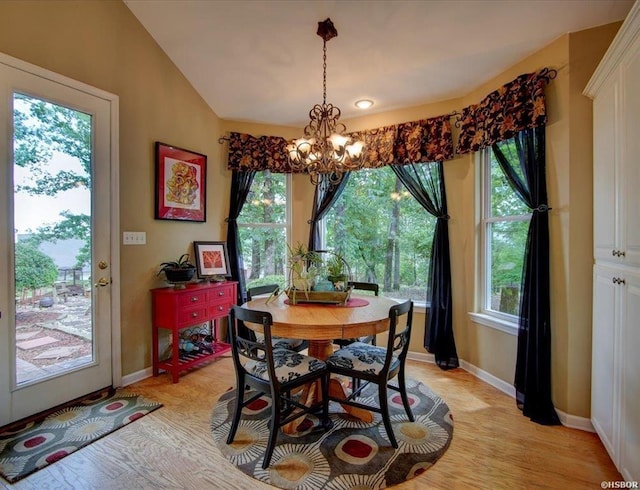 dining room with light wood-type flooring, vaulted ceiling, and a notable chandelier