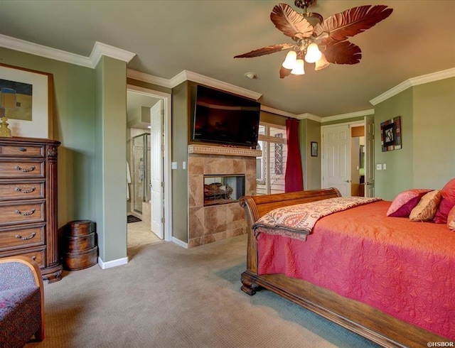 carpeted bedroom featuring crown molding, a tiled fireplace, ensuite bathroom, and ceiling fan