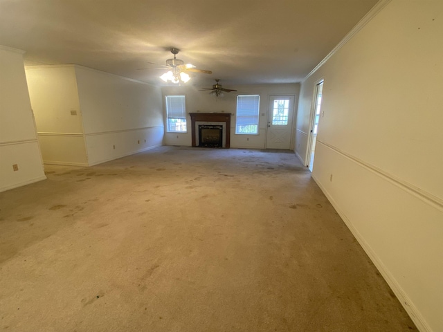 unfurnished living room with ceiling fan, carpet, and crown molding