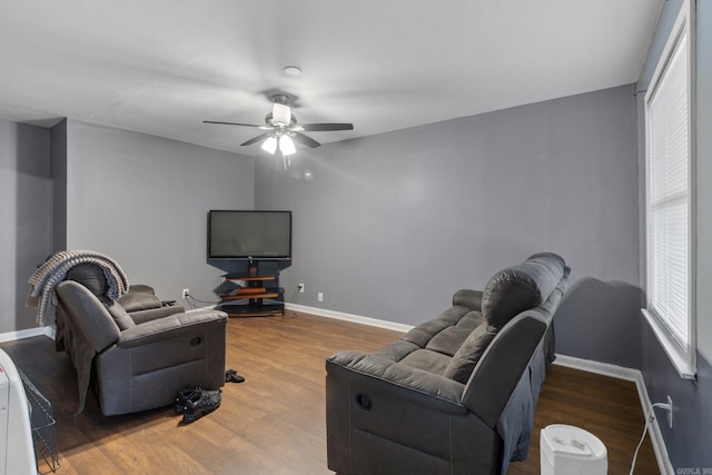 living room with ceiling fan, baseboards, and wood finished floors