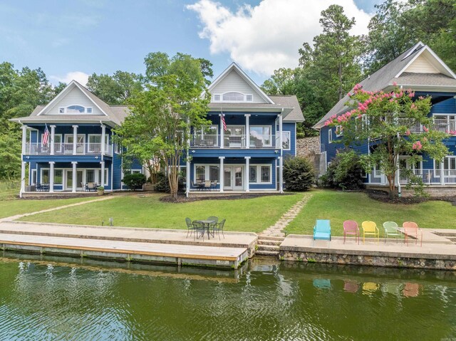 back of property with a patio, a balcony, a water view, and a yard