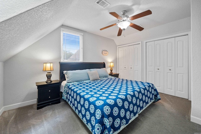 bedroom featuring lofted ceiling, carpet flooring, two closets, and visible vents