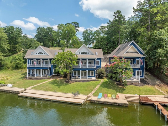 rear view of house featuring a balcony, a water view, and a lawn