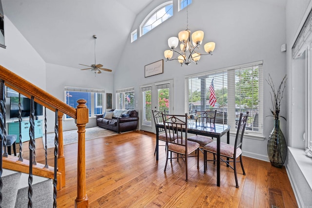 dining area featuring high vaulted ceiling, baseboards, light wood-style floors, french doors, and stairway