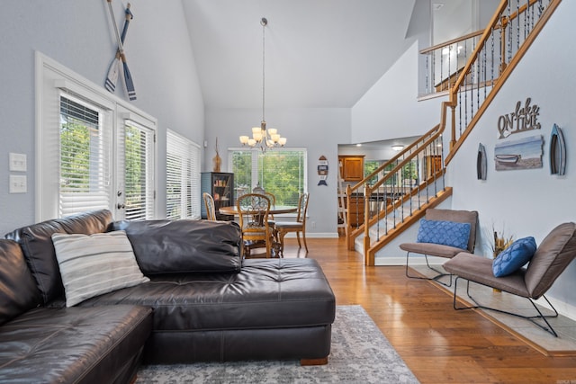 living area featuring high vaulted ceiling, a notable chandelier, baseboards, stairway, and hardwood / wood-style floors