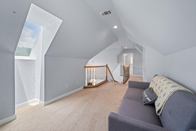 interior space with carpet, visible vents, vaulted ceiling, an upstairs landing, and baseboards