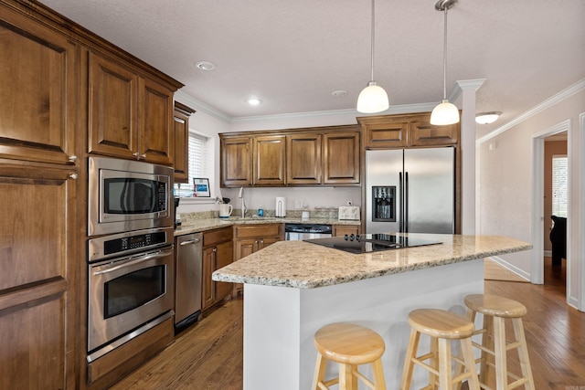 kitchen with dark wood finished floors, a breakfast bar area, a center island, crown molding, and black appliances