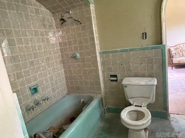 bathroom with tile walls and toilet