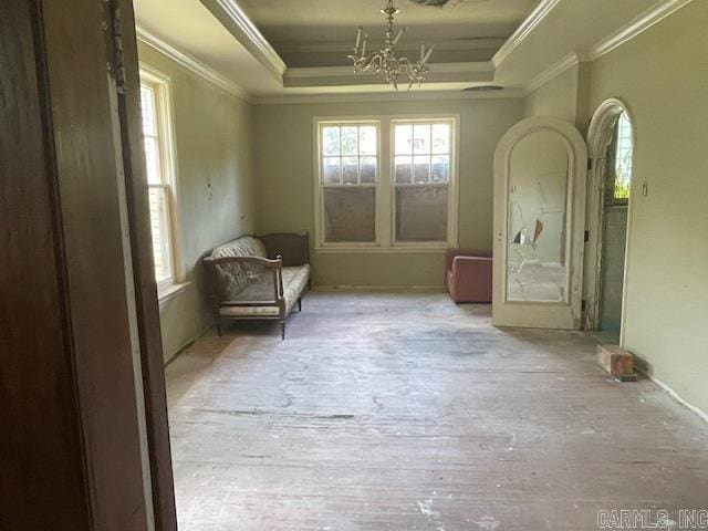 interior space featuring a raised ceiling, ornamental molding, a wealth of natural light, and an inviting chandelier