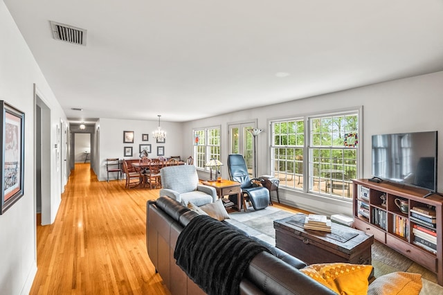 living room with an inviting chandelier and light wood-type flooring