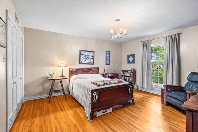 bedroom with a closet, a chandelier, and light wood-type flooring