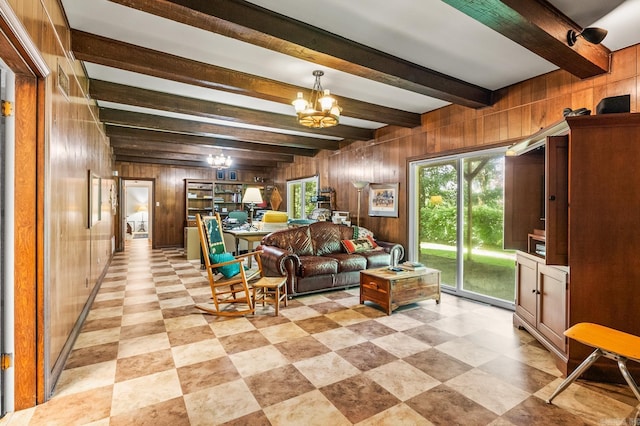 living room featuring beam ceiling, a chandelier, and wood walls