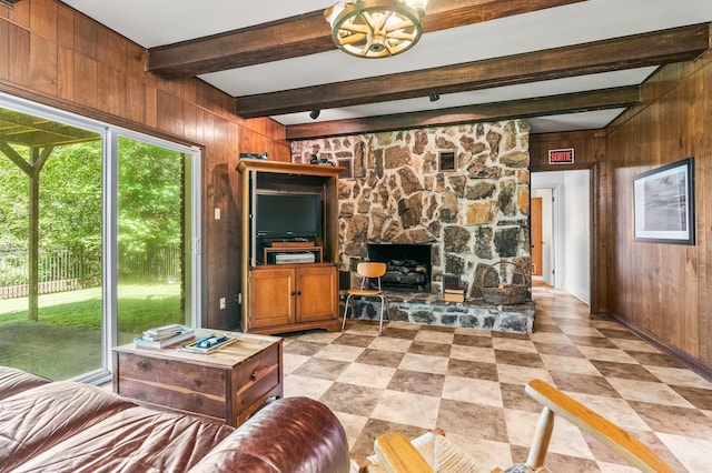 living room with beamed ceiling, a stone fireplace, and wooden walls