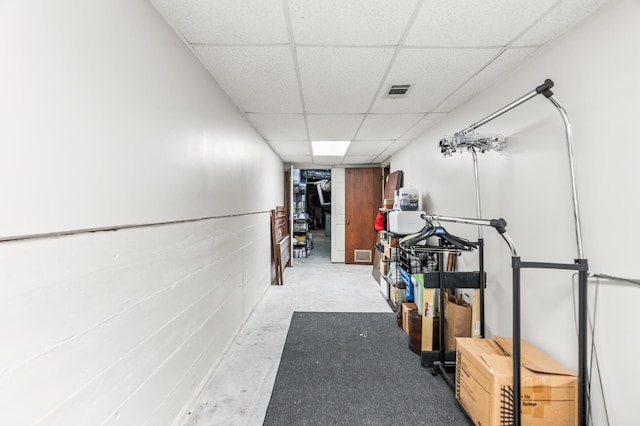 hallway featuring a paneled ceiling and concrete flooring