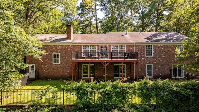 rear view of property featuring a lawn and a deck