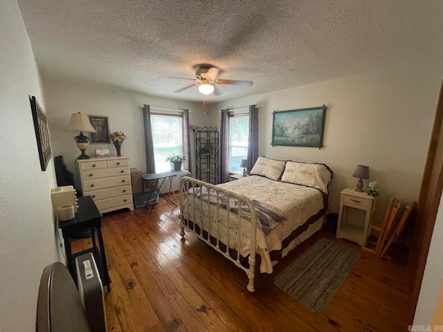 bedroom with a textured ceiling, hardwood / wood-style flooring, and ceiling fan