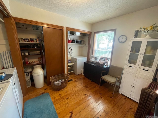 interior space with a textured ceiling, light hardwood / wood-style flooring, and independent washer and dryer