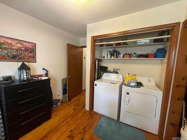 washroom with a textured ceiling, wood-type flooring, and independent washer and dryer