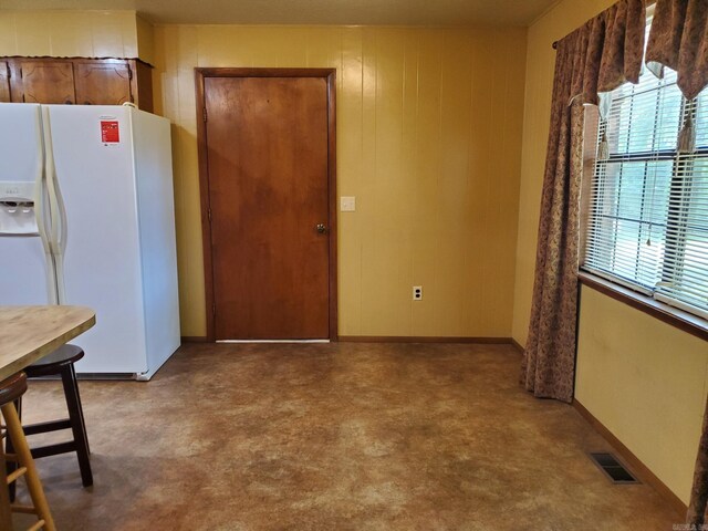 901 Hastey Ave, Mena, AR 71953 - kitchen featuring visible vents, wood walls, white refrigerator with ice dispenser, and baseboards