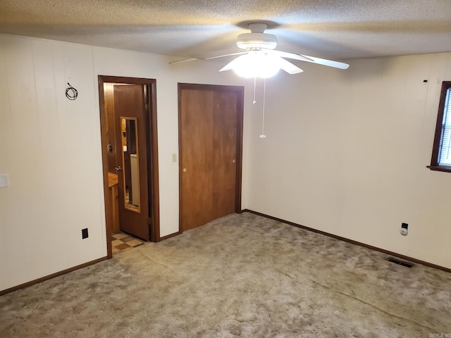 901 Hastey Ave, Mena, AR 71953 - unfurnished bedroom featuring visible vents, ceiling fan, light carpet, ensuite bathroom, and a textured ceiling