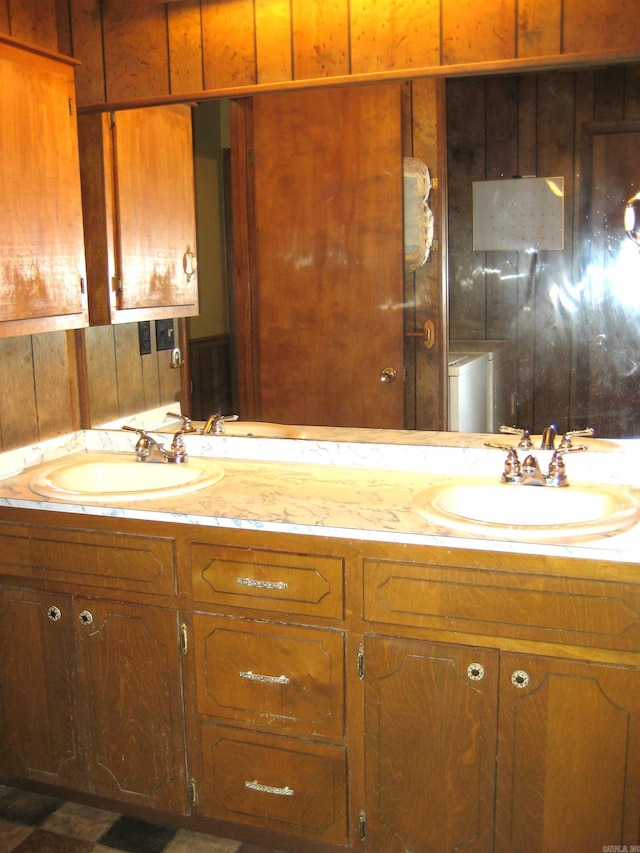 bathroom with dual vanity, washer / dryer, and wooden walls