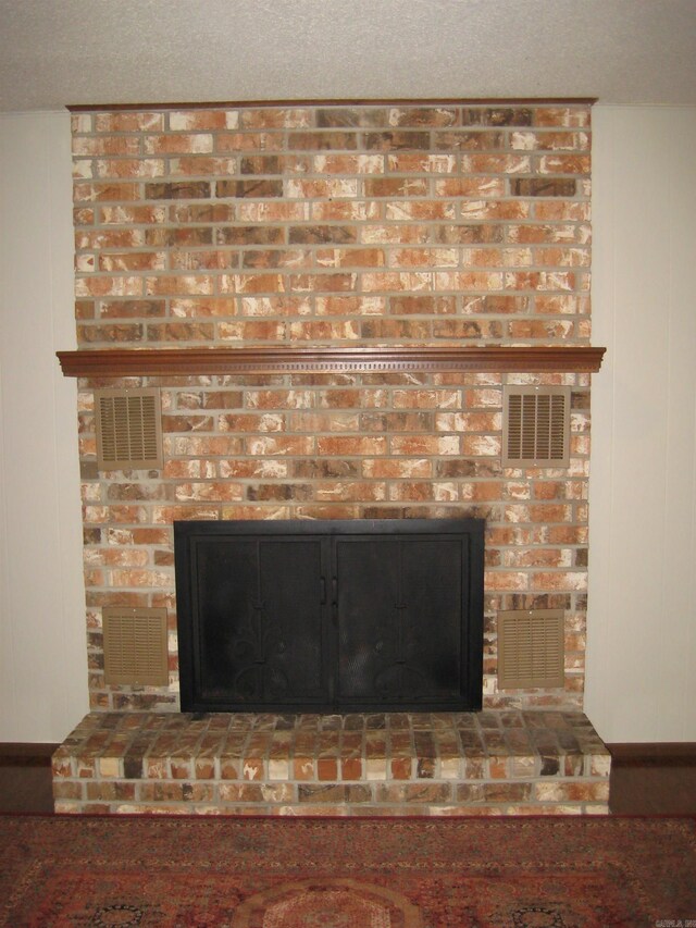 living room featuring brick wall, dark hardwood / wood-style flooring, and a brick fireplace