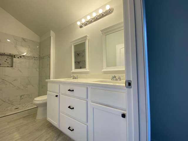 bathroom featuring vaulted ceiling, tiled shower, vanity, and toilet