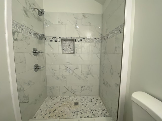 bathroom with a tile shower and toilet