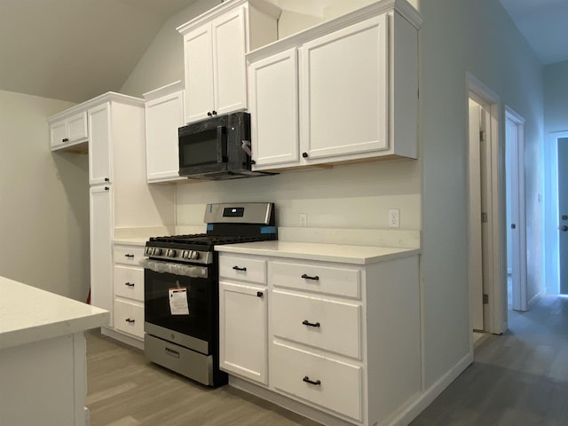 kitchen with stainless steel gas range, light hardwood / wood-style floors, and white cabinets