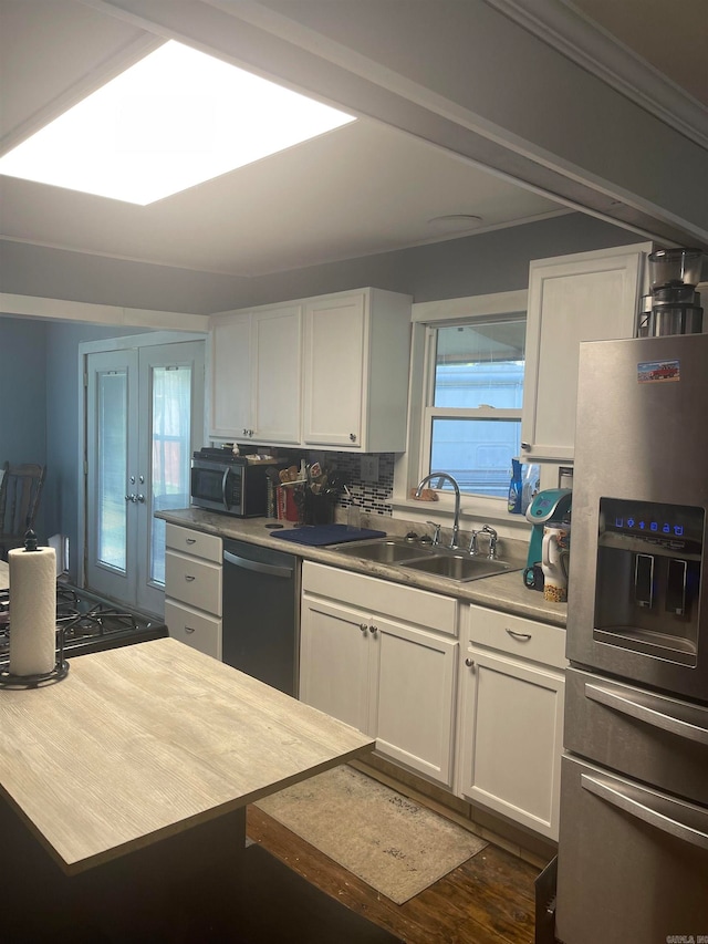 kitchen with white cabinets, stainless steel appliances, backsplash, and sink