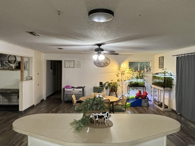 dining space with a textured ceiling, ceiling fan, dark wood-style flooring, and visible vents